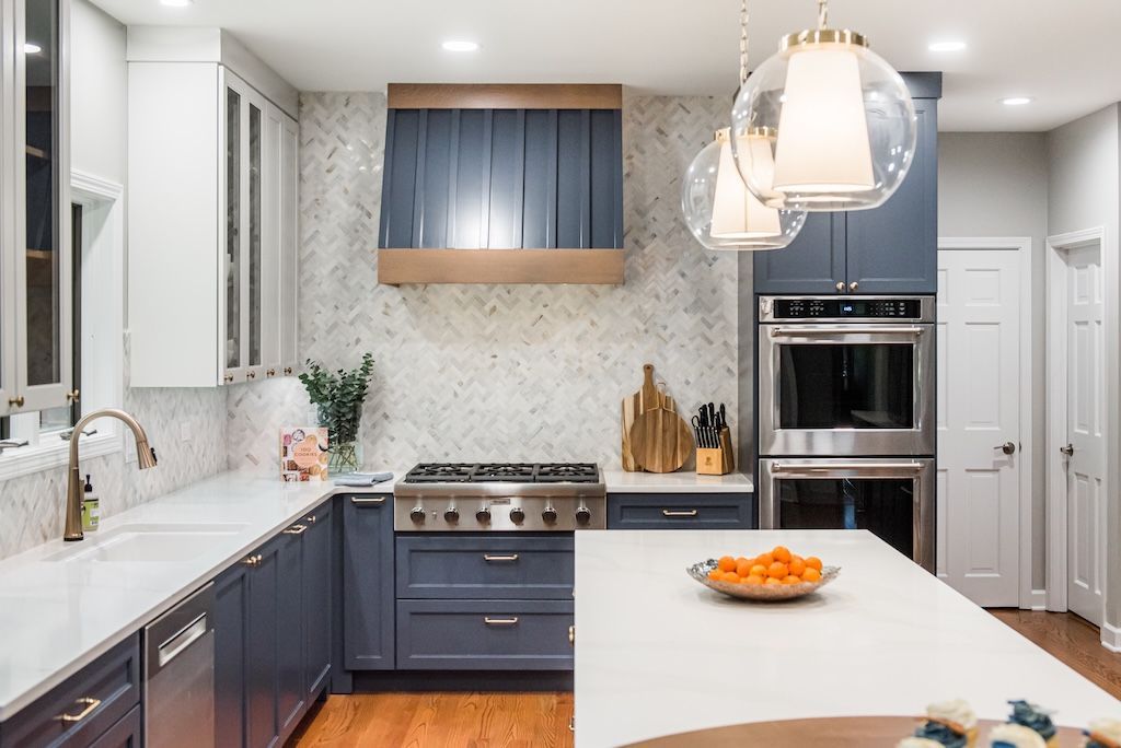 Modern kitchen with navy cabinets, white countertops, and stainless steel appliances.