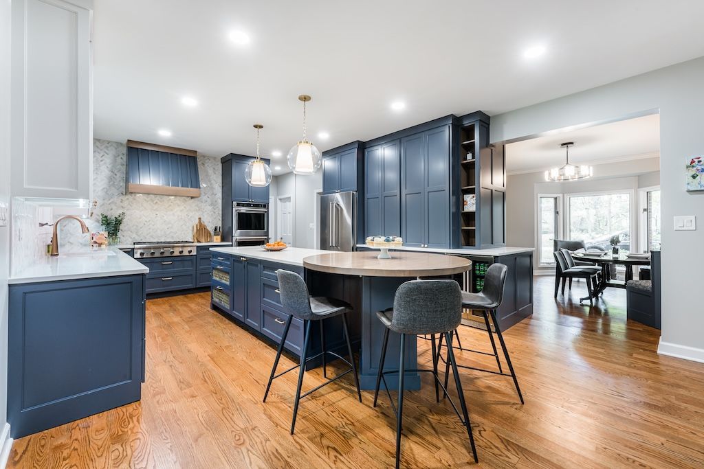 Spacious blue kitchen with island, wood floors, and dining room view.