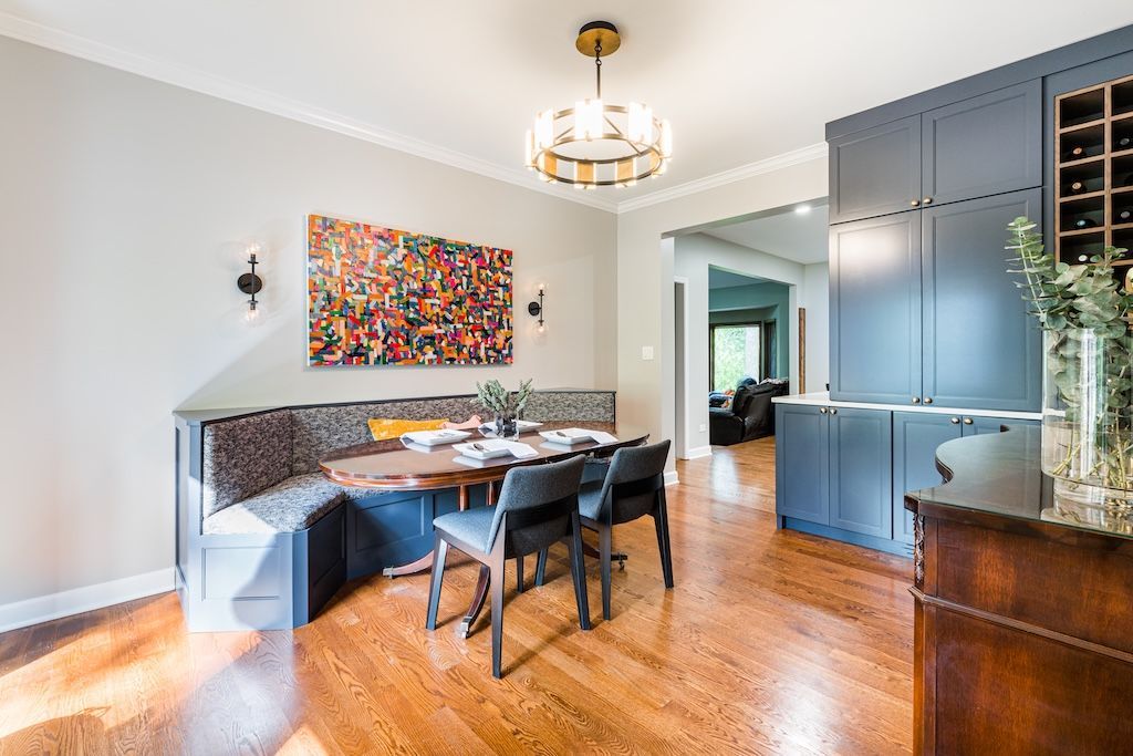 Dining room with built-in seating, art, a table, and chairs. Blue cabinetry and wood flooring are present.