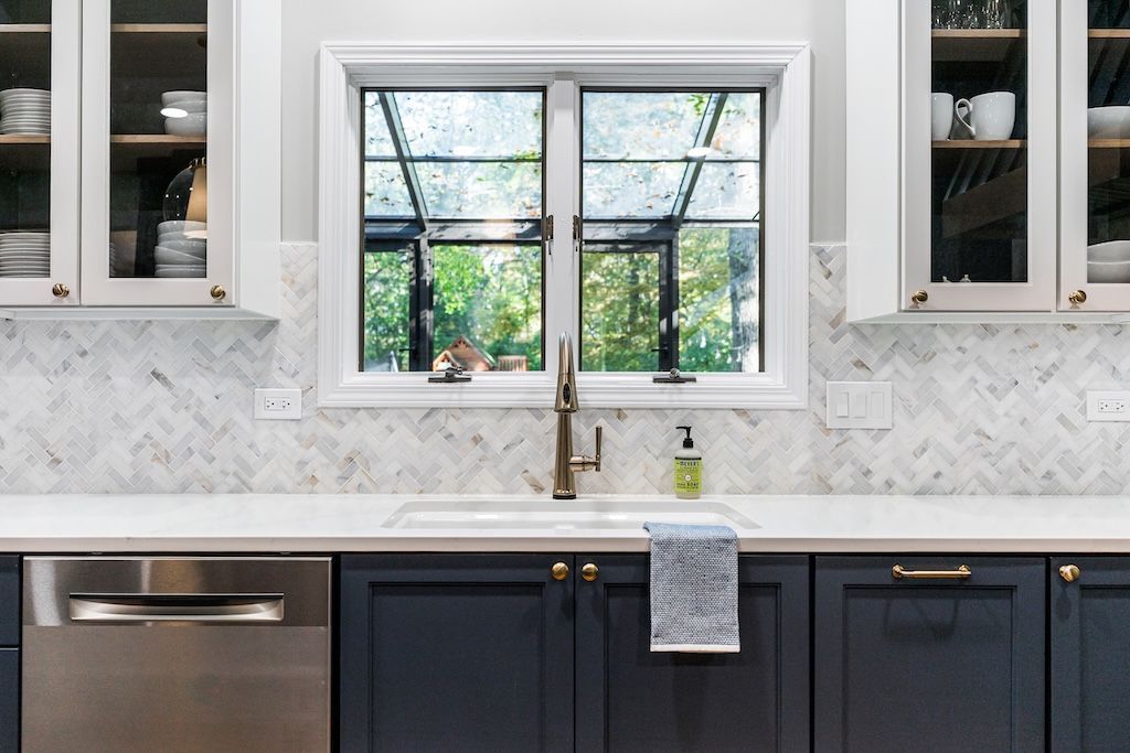 Kitchen with navy cabinets, white countertops, and a window above the sink.