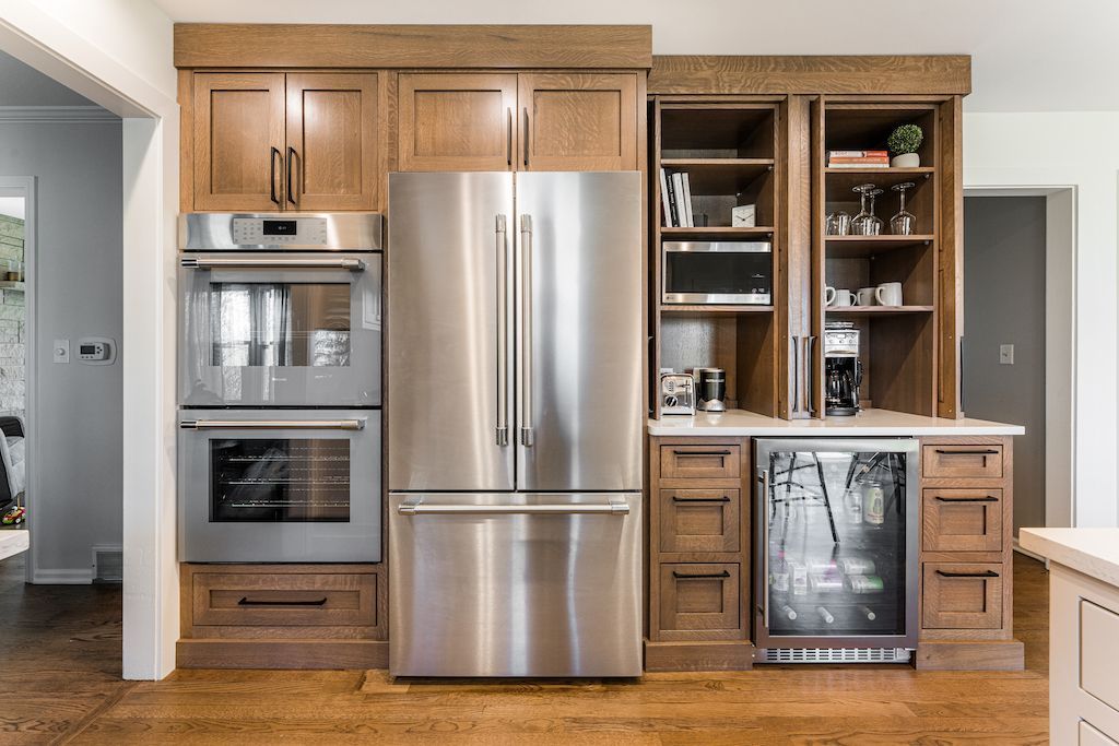 Kitchen with built-in appliances: oven, refrigerator, beverage cooler, and open shelves with glassware.