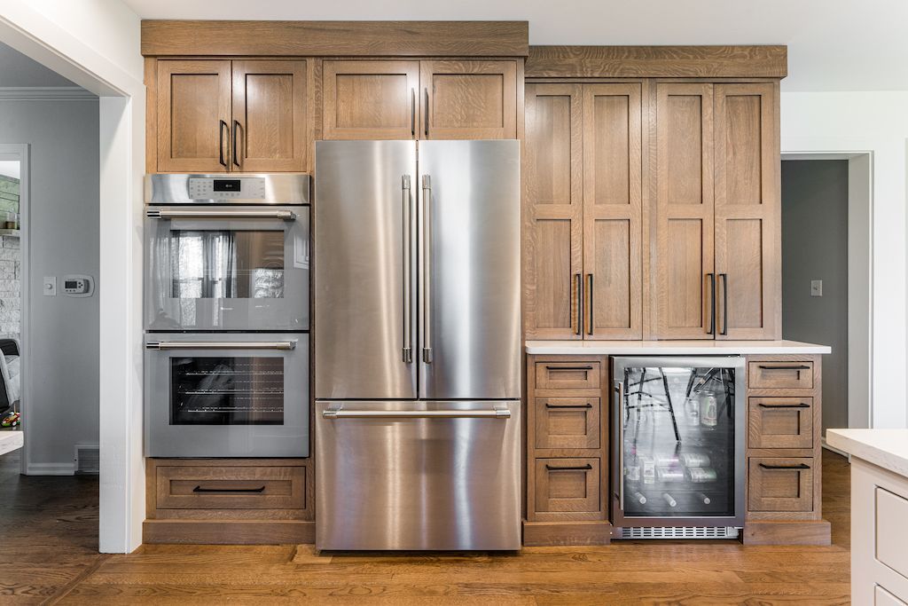 Built-in kitchen appliances: oven, refrigerator, wine cooler, and cabinets made of light brown wood.