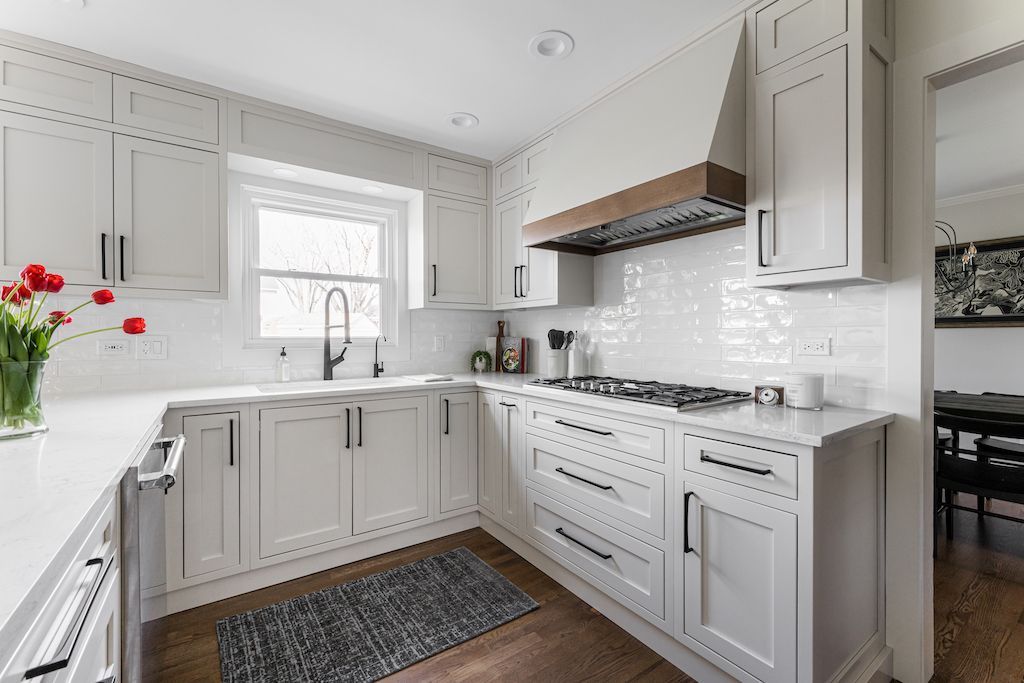 White kitchen with cabinetry, tile backsplash, range, and hood.