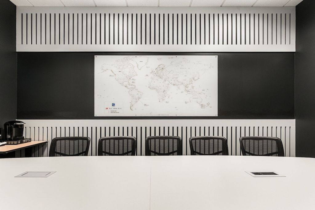 Conference room with a world map, white table, black wall, and chairs.