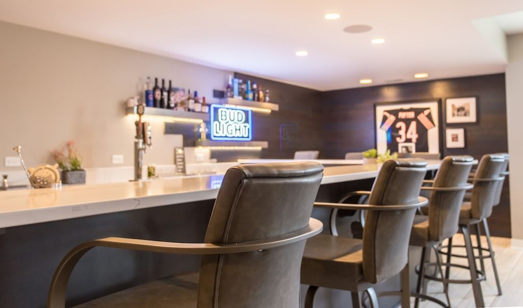 Bar area with stools, beer taps, neon sign, and sports memorabilia.