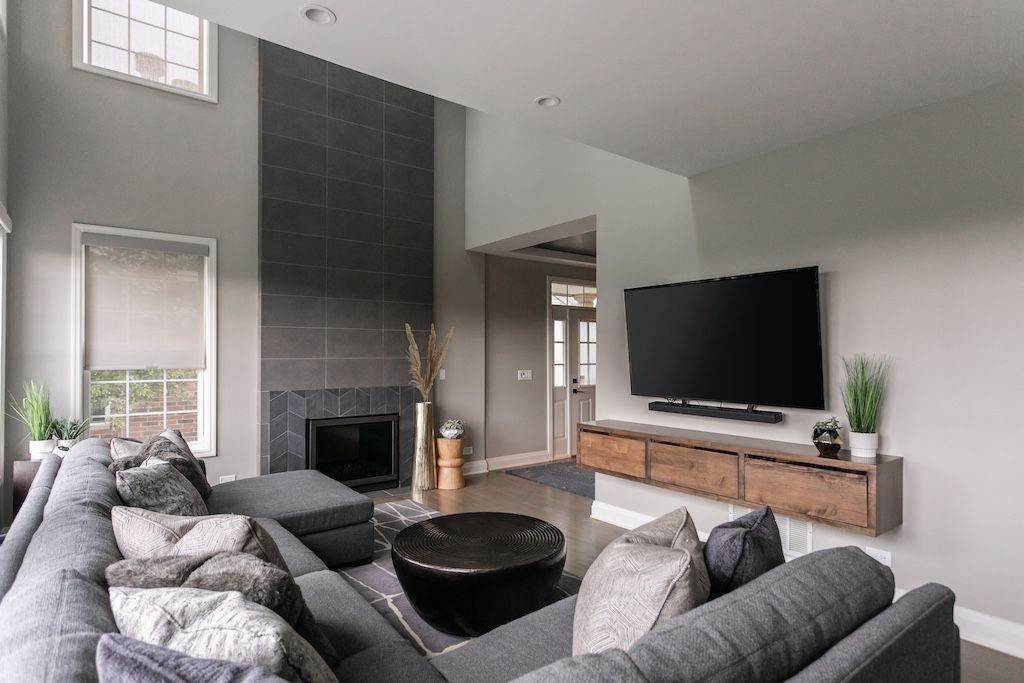 Gray living room with a sectional sofa, mounted TV, and fireplace.