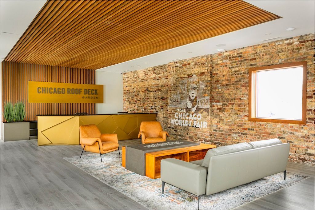 Lobby with wood and brick accents; seating area with modern furniture; Chicago Roof Deck & Garden sign.