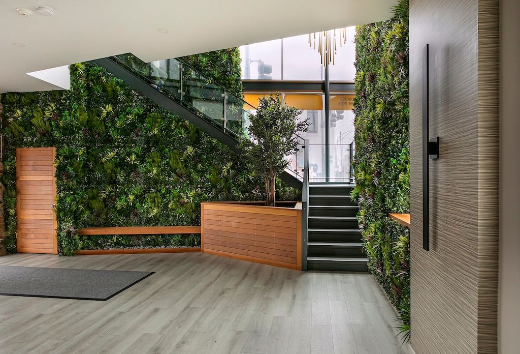 Lobby with green wall, wooden accents, stairs, and natural light from large windows.