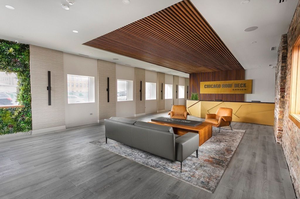 Modern office lobby with wood ceiling, green wall, gray sofa, and reception desk.