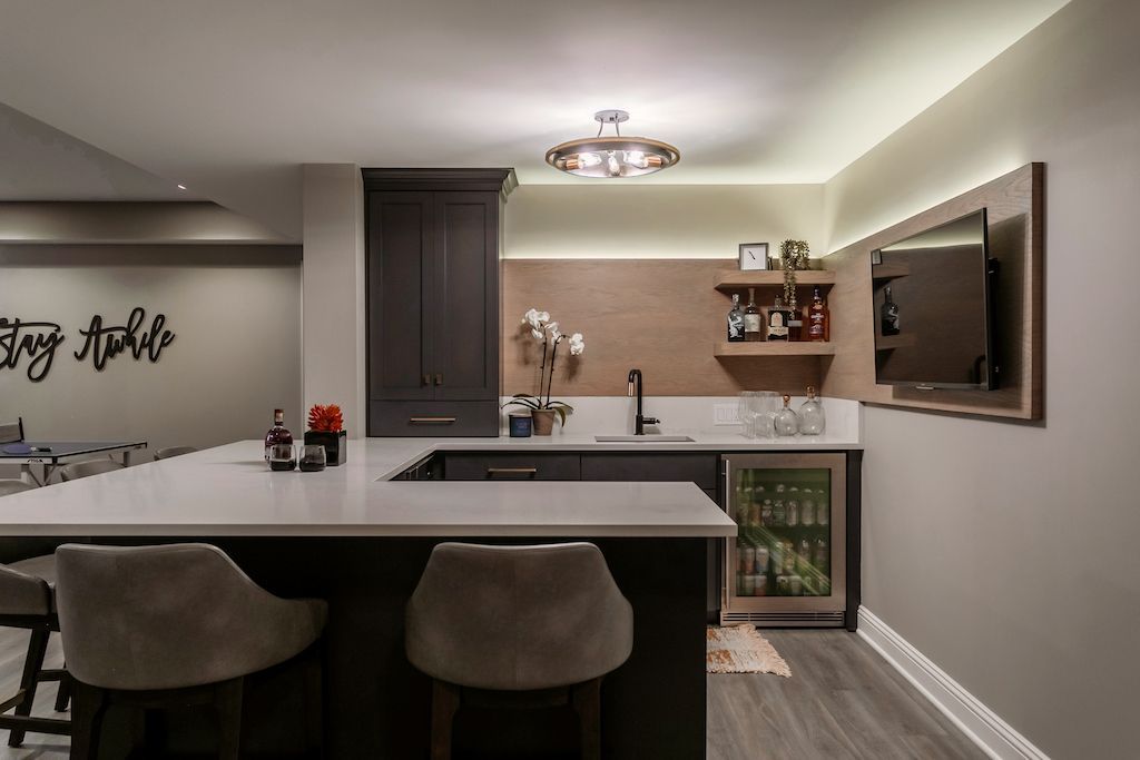 Bar area with countertop, seating, cabinets, sink, mini fridge, TV, and decorative items.