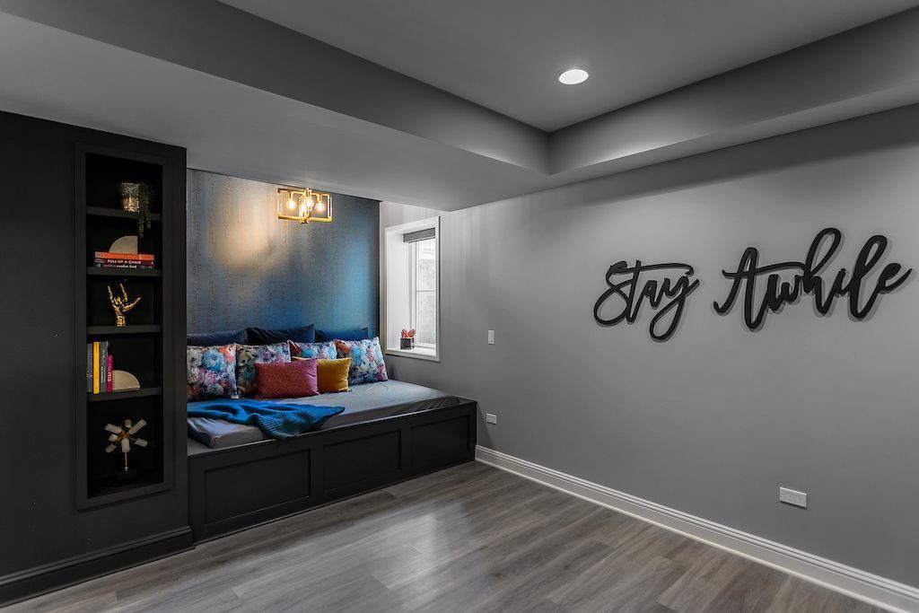 Cozy built-in reading nook with dark blue/gray walls, a bench, bookshelves, and 