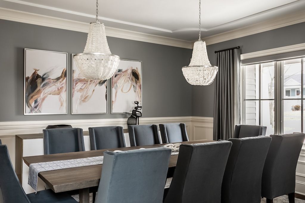 Elegant dining room with large table, blue upholstered chairs, and crystal chandeliers.