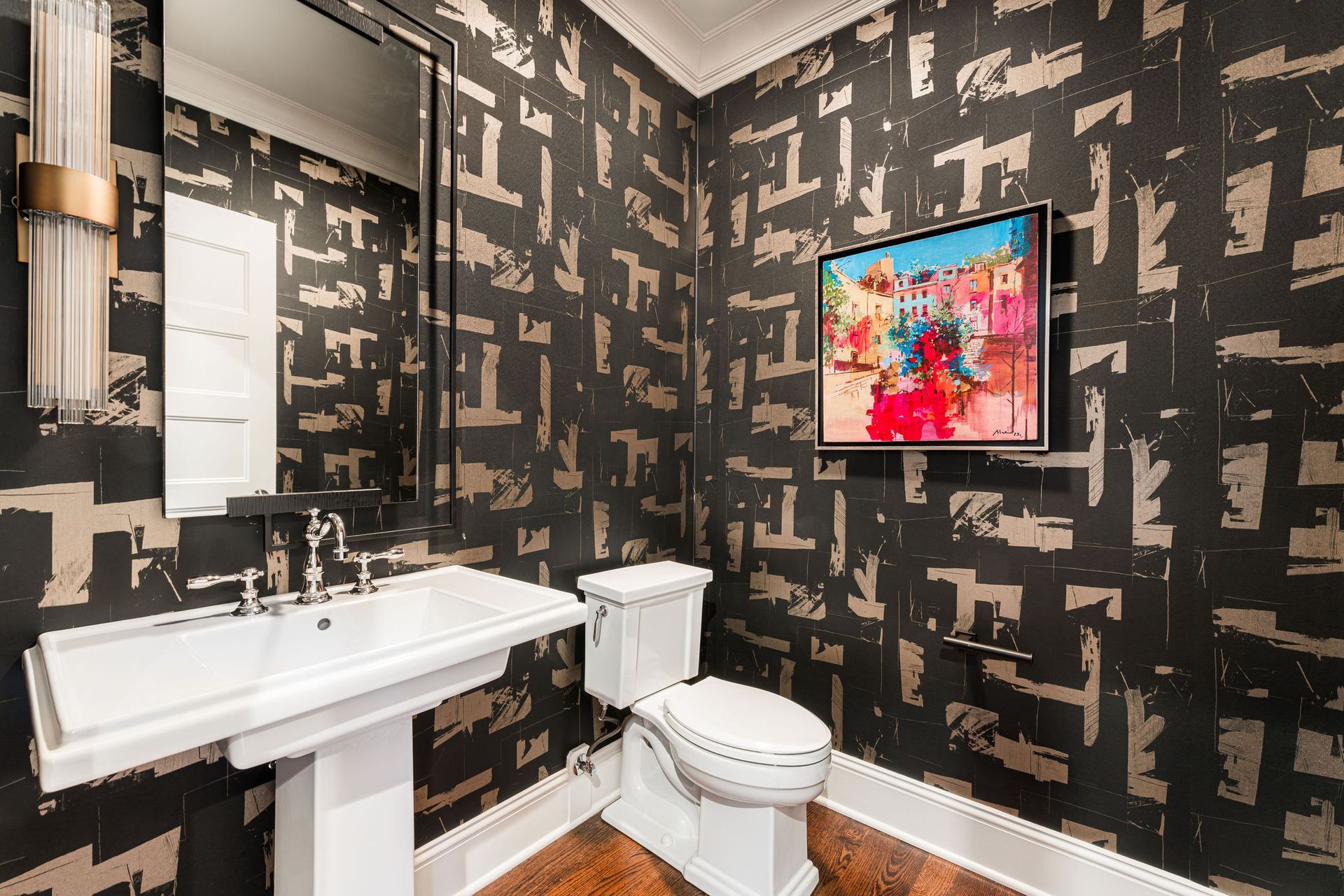 Powder room with patterned wallpaper, pedestal sink, toilet, and artwork.