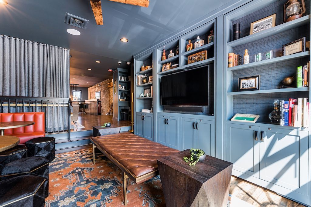 Living room with built-in bookshelves painted blue, a leather bench, and a red booth.