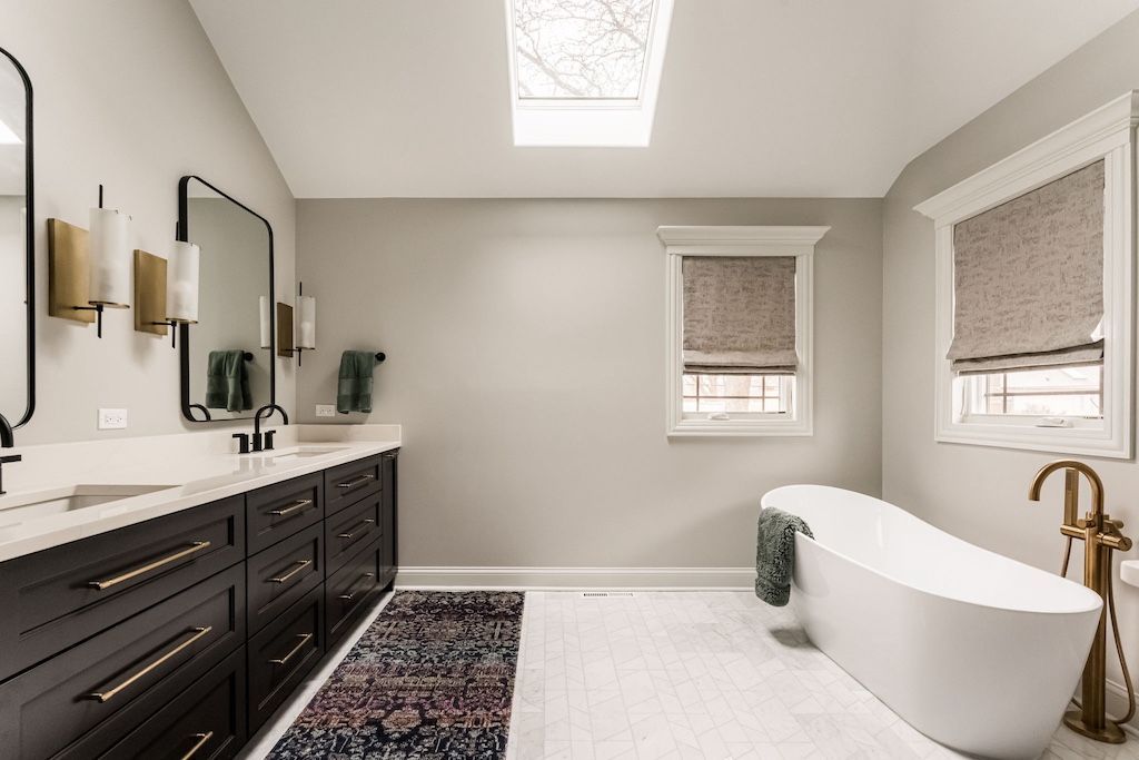 Modern bathroom with dark vanity, freestanding tub, and neutral color scheme.