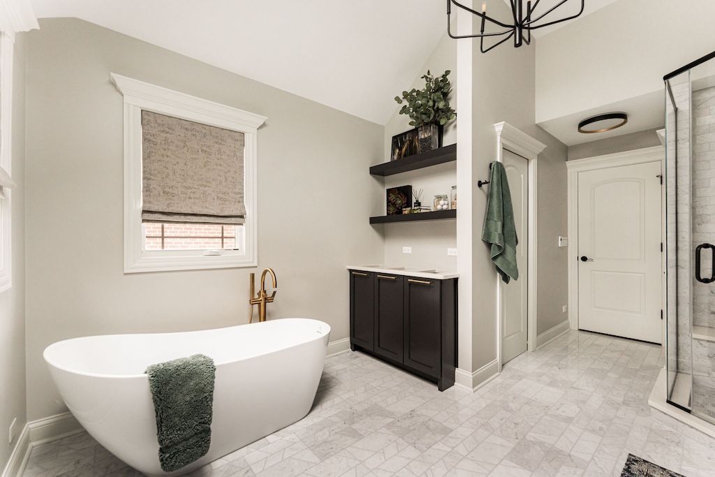 Modern bathroom with a white tub, dark cabinets, shelves, and a large window.