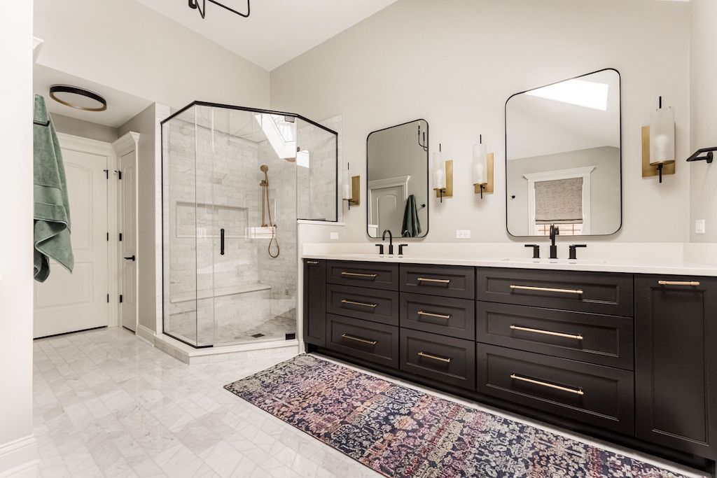 Modern bathroom with dark cabinets, a glass shower, and patterned rug.
