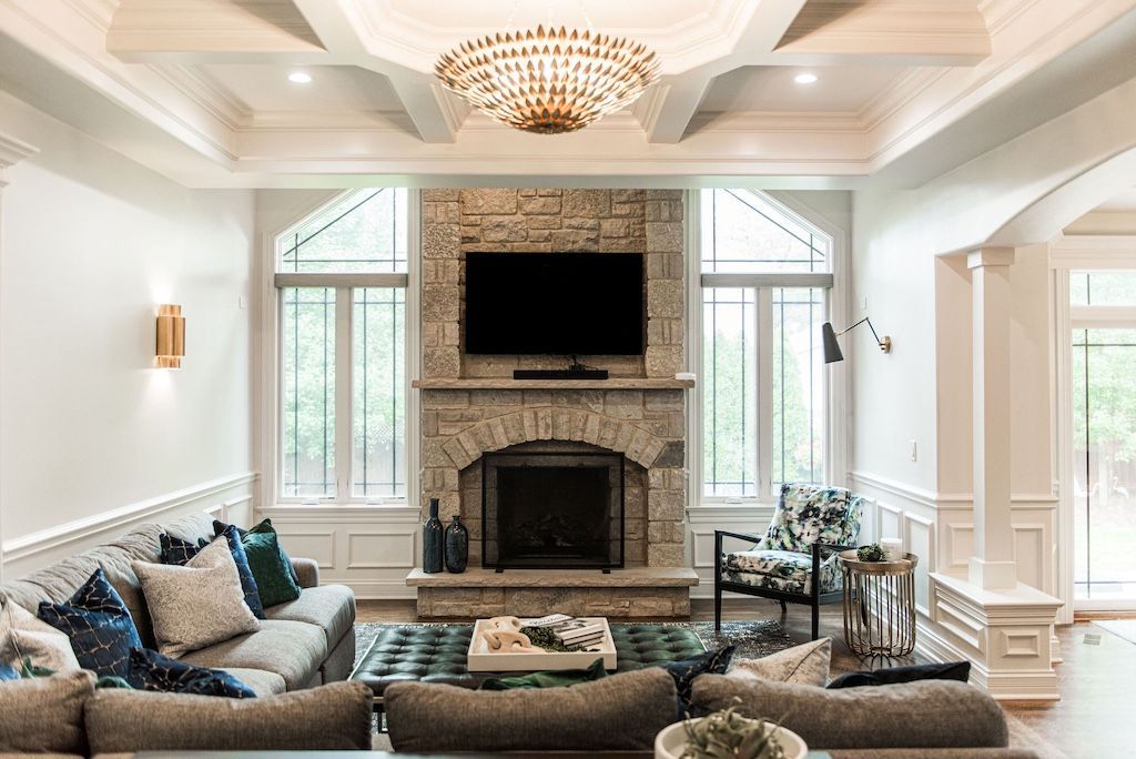 Living room with stone fireplace, TV, windows, and two couches.