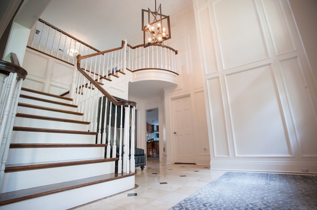 Grand foyer with a winding staircase, white walls, and a chandelier.