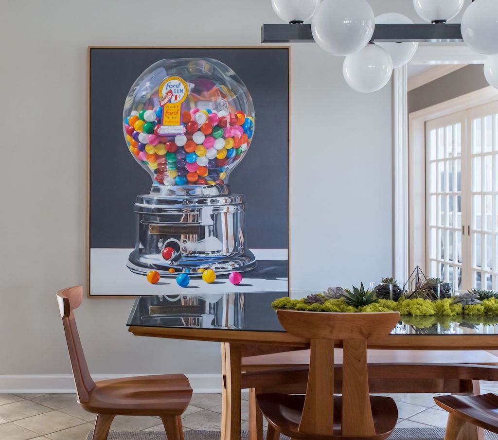 Dining room with gumball machine art, wooden table, and modern light fixture.
