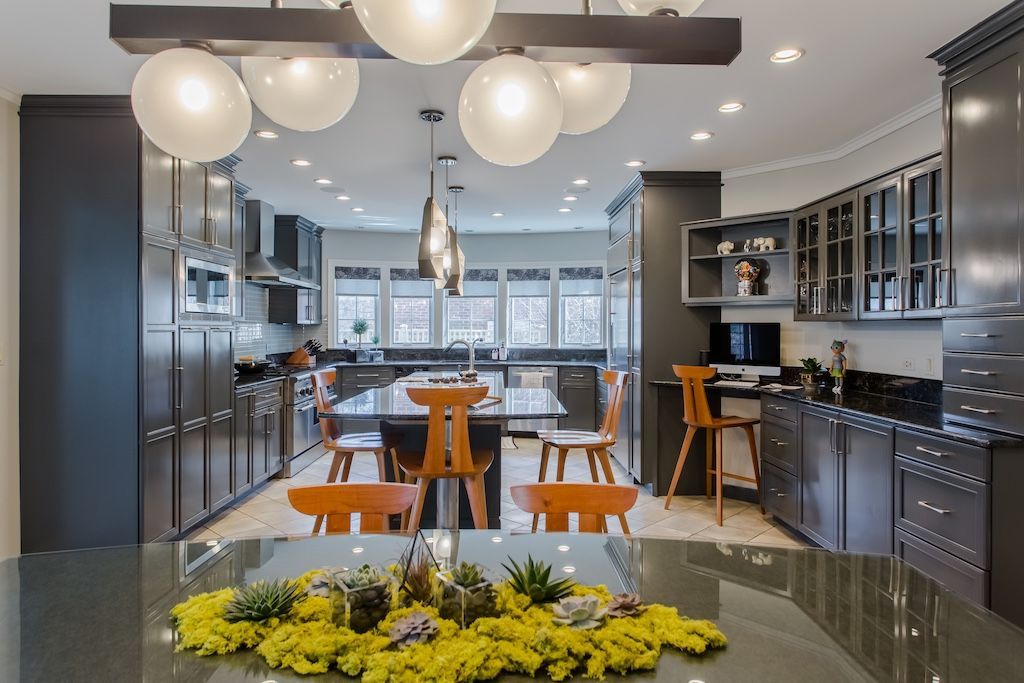 Modern kitchen with gray cabinets, wooden chairs, and large island with floral centerpiece.