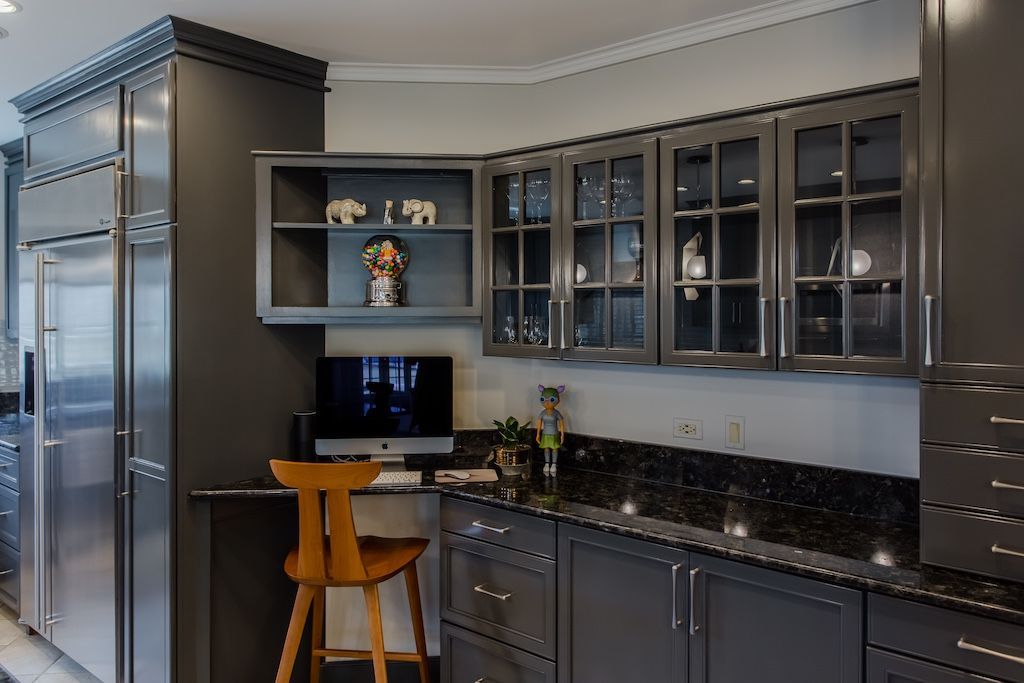 Dark gray kitchen with stainless steel appliances, open shelving, and glass-front cabinets.