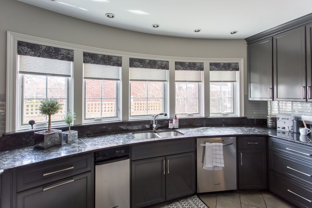 Dark gray kitchen with curved windows, granite countertops, and stainless steel appliances.