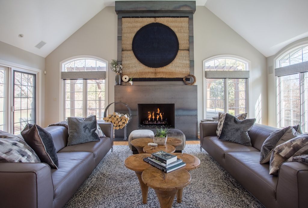 Spacious living room with fireplace, two gray leather sofas, and a patterned rug.