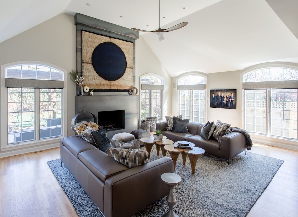 Spacious living room with a brown leather sectional, fireplace, and arched windows.