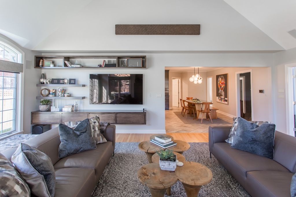 Modern living room with leather sofas, wood coffee tables, and built-in entertainment center.
