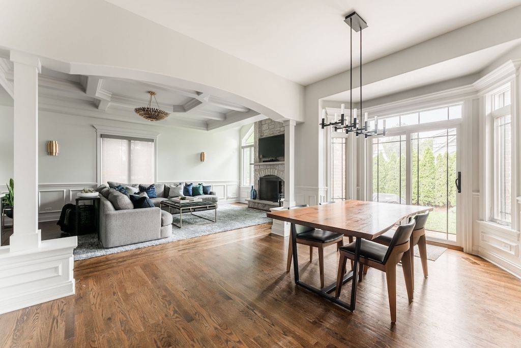 Spacious open-concept room with wood floors, dining table, fireplace, and large windows.