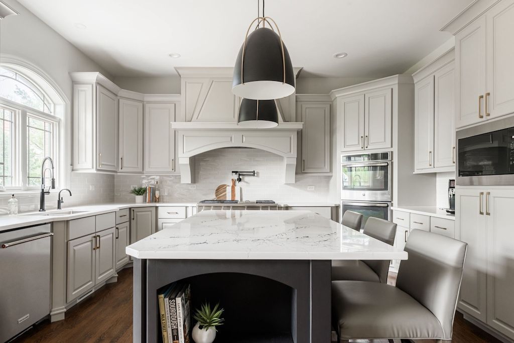 Modern kitchen with gray cabinets, white countertops, dark island, and a black light fixture.