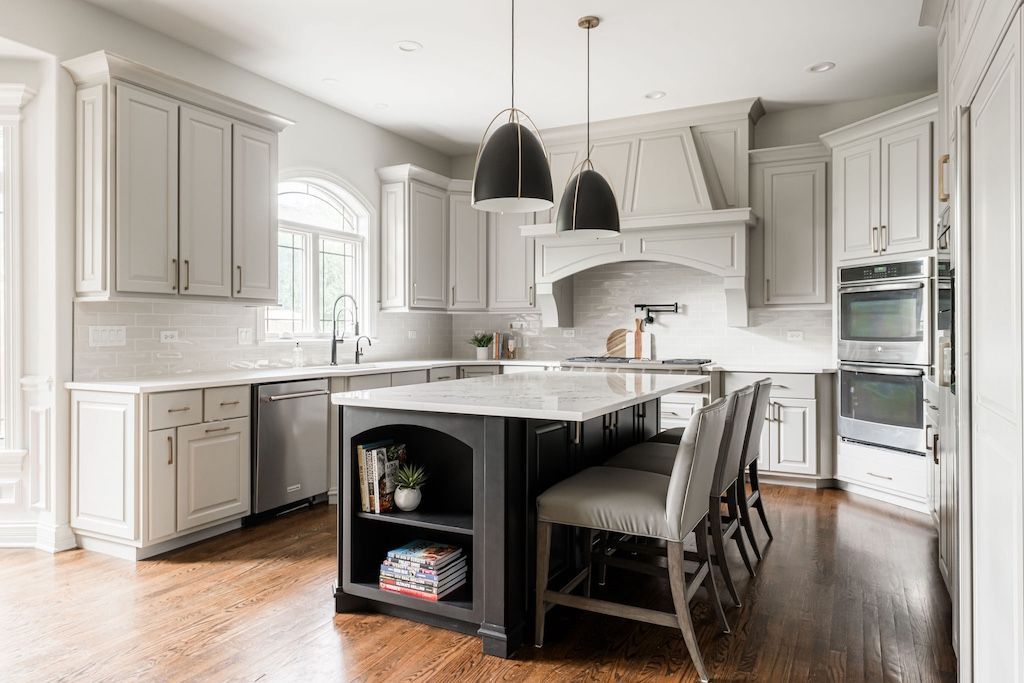 Modern kitchen with white cabinets, dark island, and pendant lights over the island.