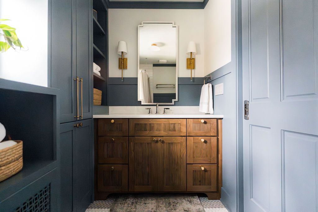 Bathroom with a wooden vanity, a large mirror, and blue walls and cabinetry.