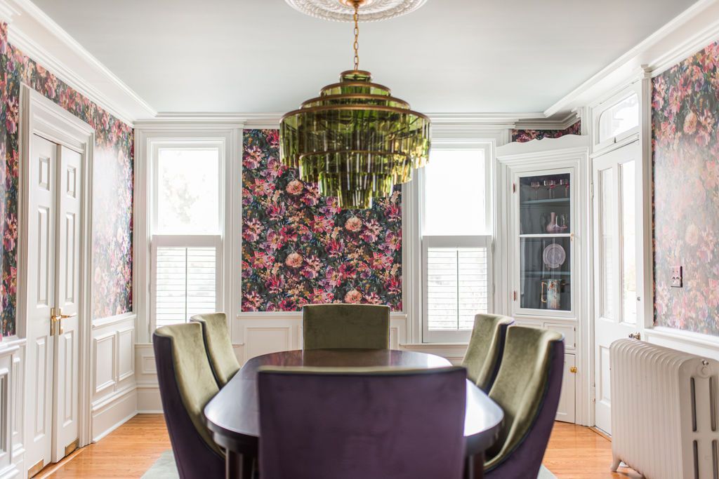 Dining room with floral wallpaper, purple chairs, and a gold chandelier.