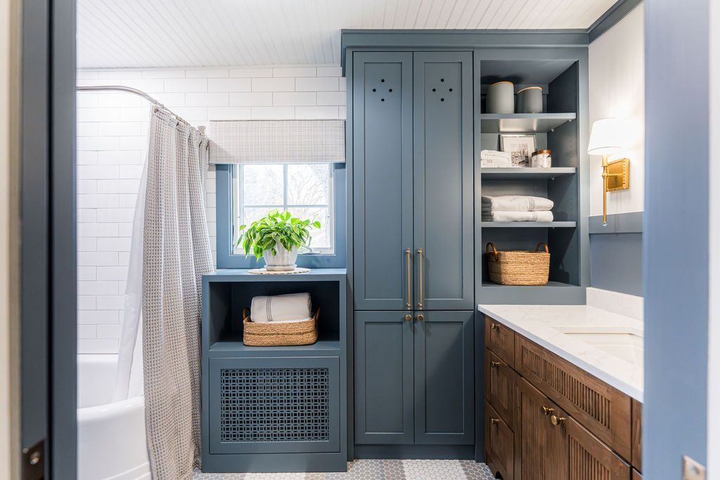 Bathroom with blue and brown cabinetry, white tile, and a striped shower curtain.