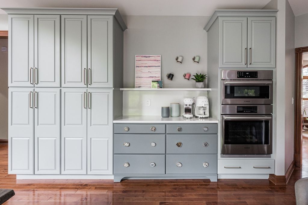 Kitchen cabinets in shades of gray with stainless steel appliances and countertop.
