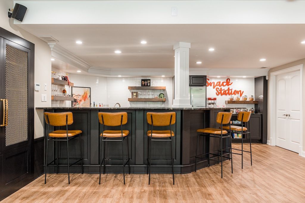 Basement bar with dark gray cabinets, yellow bar stools, and 