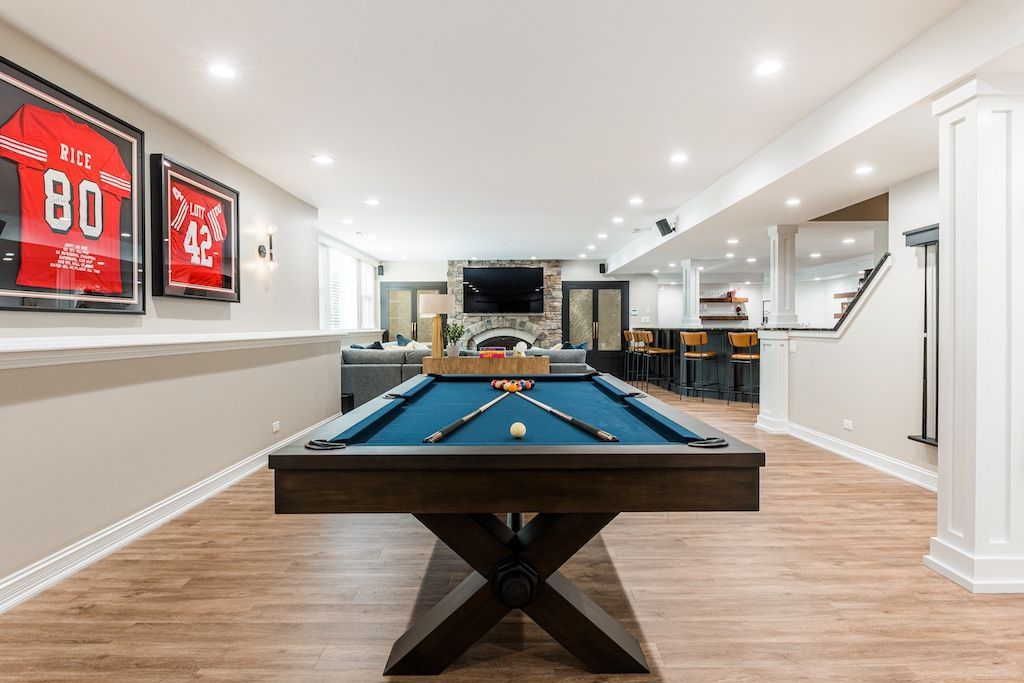 A finished basement with a pool table, sports memorabilia, and a bar.
