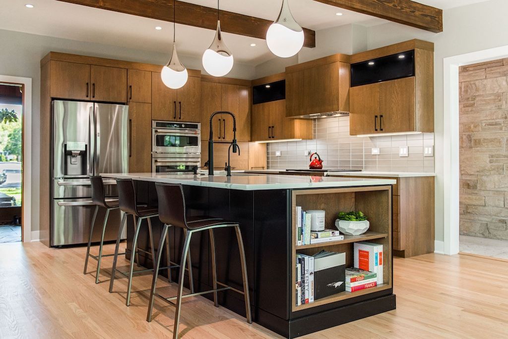 Modern kitchen with wood cabinets, black island with stools, and stainless steel appliances.
