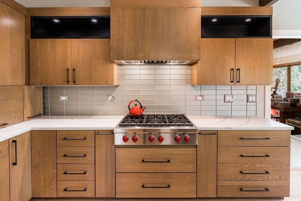 Modern kitchen with wood cabinets, white countertops, and stainless steel appliances.