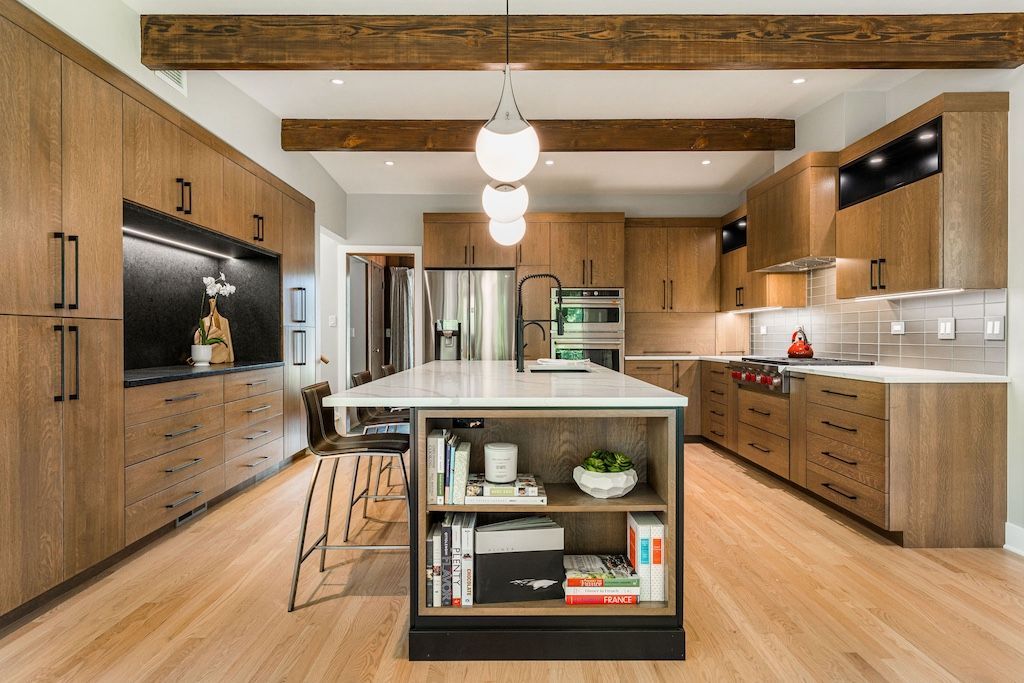 Modern kitchen with light wood cabinets, white island, and hardwood floors.