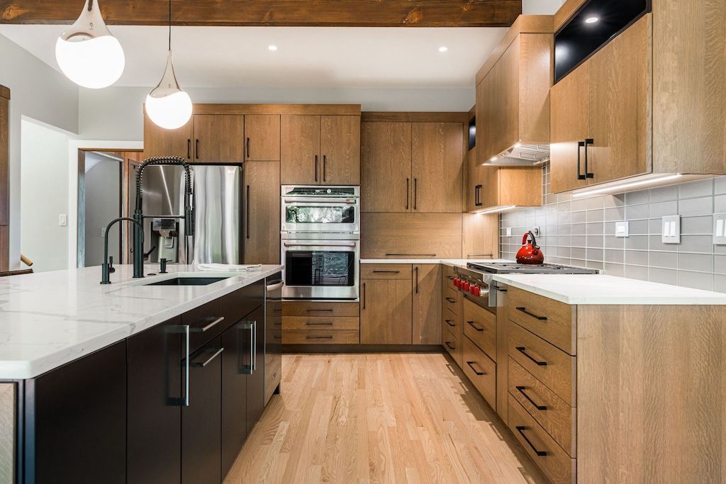 Modern kitchen with wooden cabinets, stainless steel appliances, and a black island.