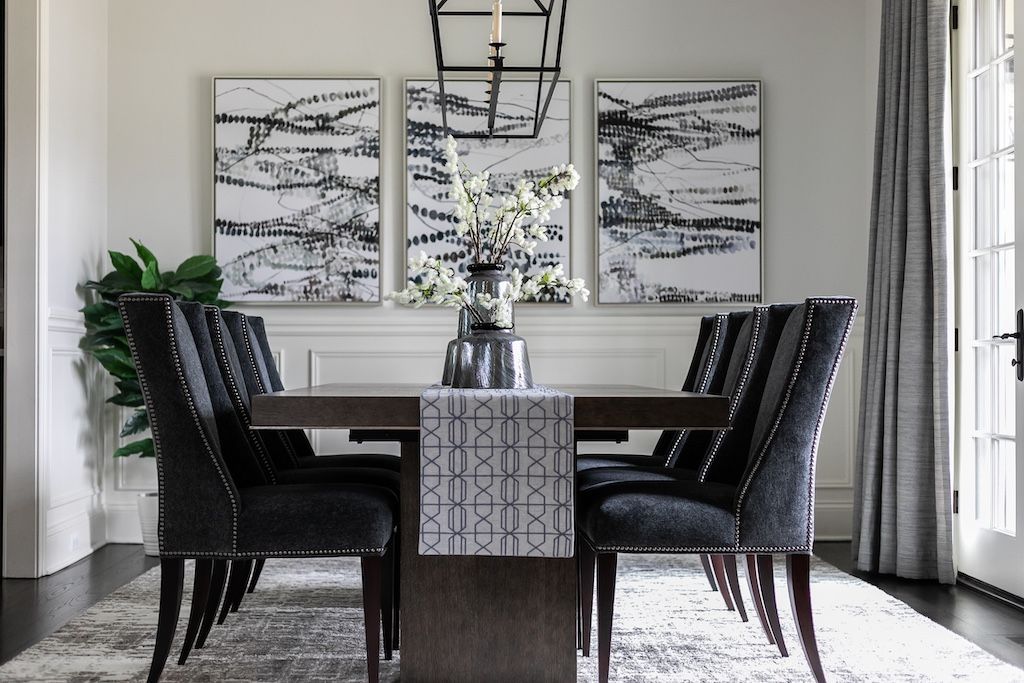 Dining room with dark table, gray chairs, artwork, and chandelier.