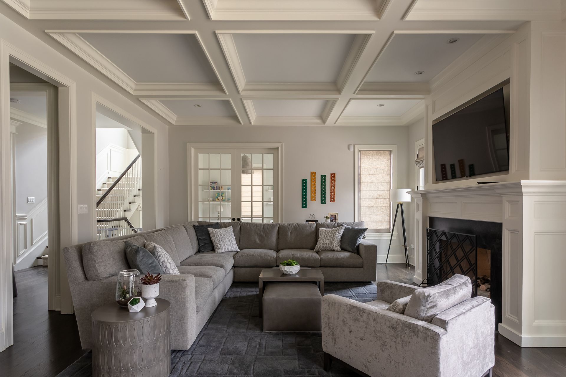 Living room with gray sectional, fireplace, TV, and coffered ceiling.