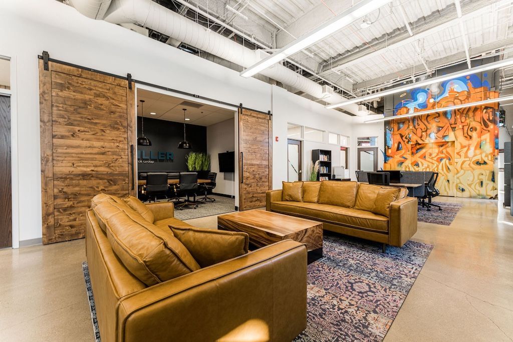 Lounge area with brown leather couches, rustic sliding doors, and a colorful mural.