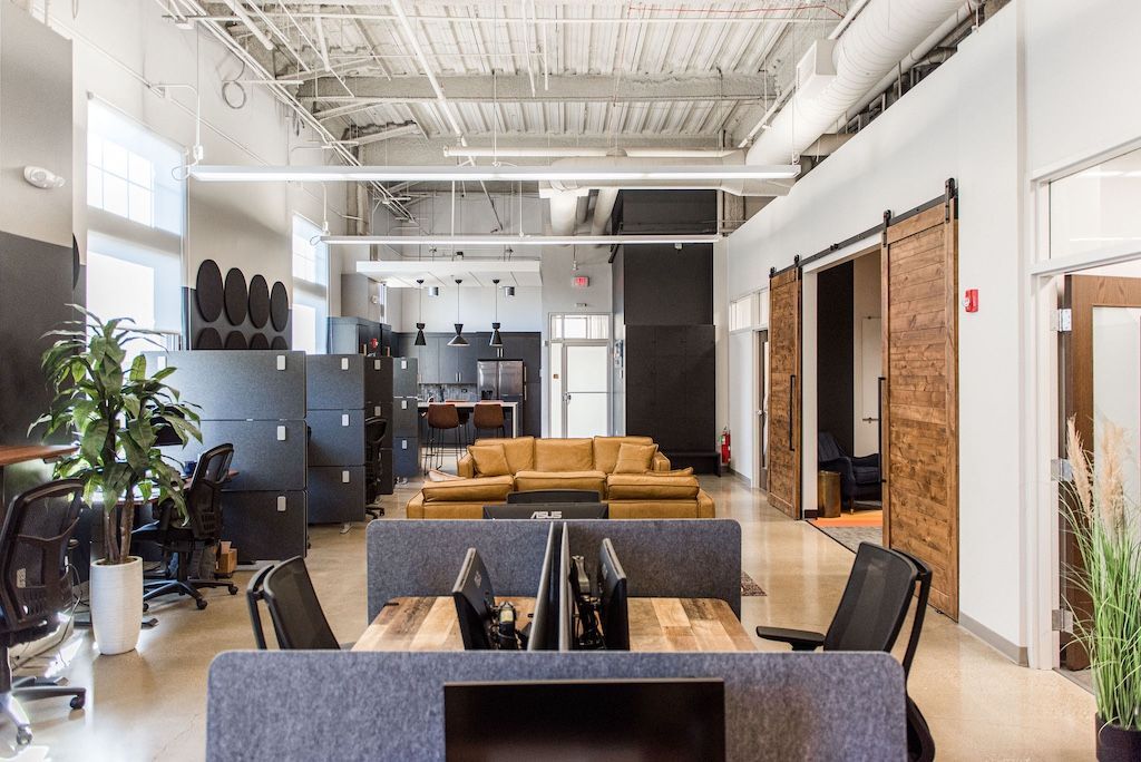 Modern office space with desks, a lounge area with a sofa, and large sliding doors.