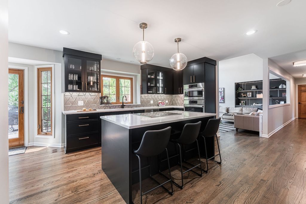 Modern kitchen with dark cabinetry, large island, light countertops, and wood flooring.