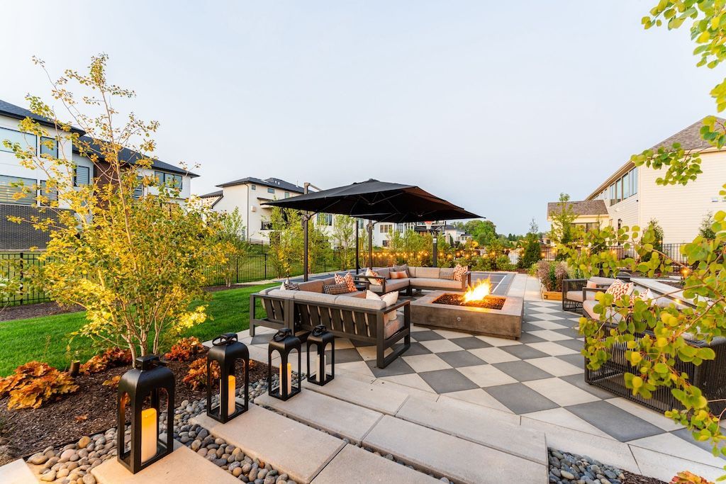 Outdoor patio with fireplace, seating, umbrella, and lanterns. Checkerboard stone pathway.