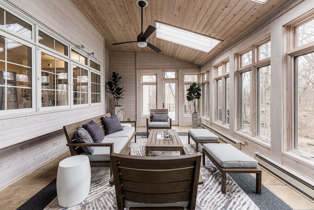 Sunroom with wood ceiling and floors, large windows, and modern outdoor furniture.